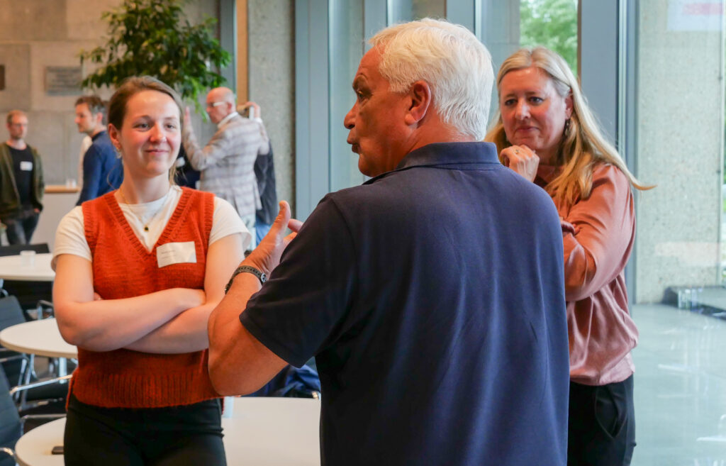 Andries Osseman is een verhaal aan het vertellen. Twee dames staan erbij te luisteren.