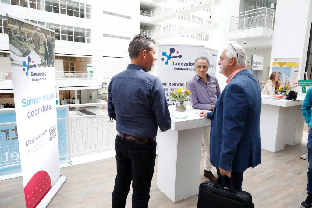 Drie mannen in gesprek op de Open Gov Week 2024 bij de stand van Grenzeloos Datalandschap