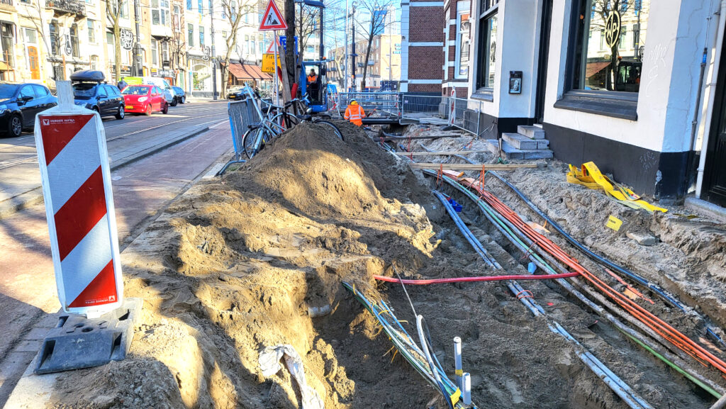 Straat grond ligt open waarbij vele kabels en leidingen te zien zijn.